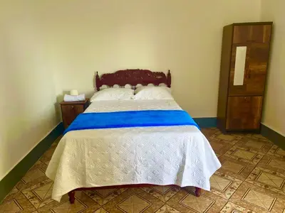 a bedroom with a bed with a blue and white bedspread at Casa Límaco in Ayacucho