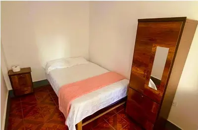 a small bedroom with a bed and a dresser at Casa Límaco in Ayacucho