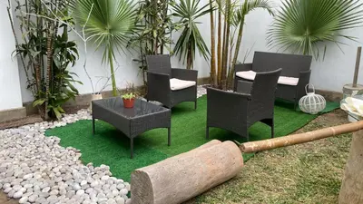 a patio with chairs and a table on grass at 2 beds with garden view and terrace in Lima