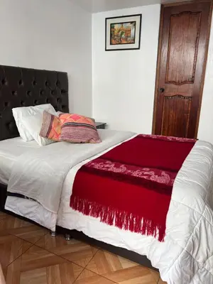 a bed with a red and white blanket on it at Redys House in Cusco