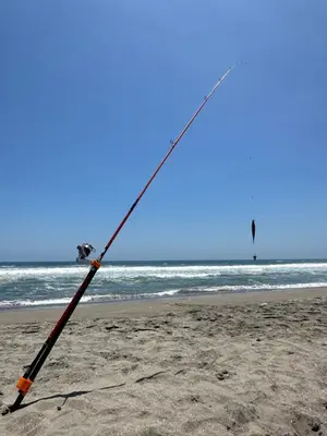 a fishing rod on a beach with the ocean at Refugio del Mar Wakama in San Vicente de Cañete