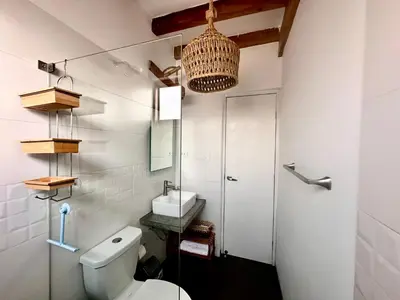 a white bathroom with a toilet and a sink at Refugio del Mar Wakama in San Vicente de Cañete