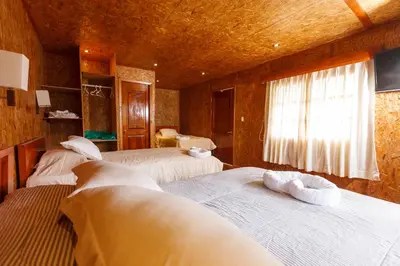 a bedroom with three beds and a window at Cabañitas San José in Oxapampa