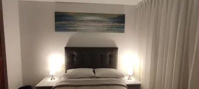 a bedroom with a bed with two lamps and a painting at Sumaq Apartment Lima Airport in Lima