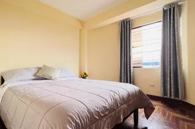 a bedroom with a large bed and a window at Kusi Wasi in Cusco