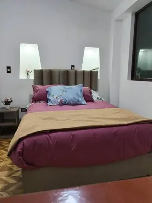 a bedroom with a large bed with purple sheets and pillows at Cori Wasi in Cusco