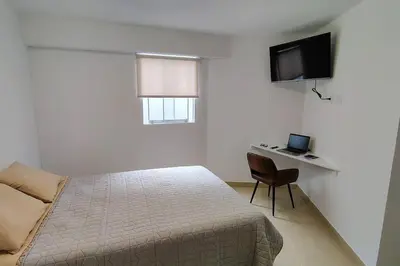 a bedroom with a bed and a desk and a television at Departamento en playa Arica in Lurín