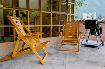 two wooden chairs sitting on a porch next to a grill at Spacious entire house with awesome mountain views in Urubamba