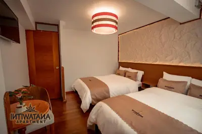 a hotel room with two beds and a table at Intiwatana Apartment in Cusco