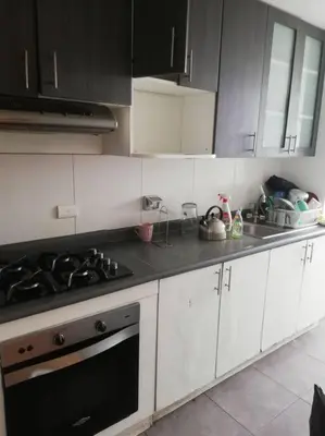 a kitchen with white cabinets and a stove top oven at Apartamento 3Hab Seguridad y Cerca del Aeropuerto in Lima