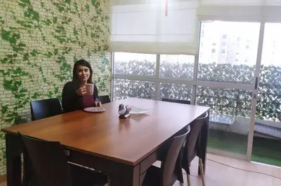 a woman sitting at a table in a room at Apartamento 3Hab Seguridad y Cerca del Aeropuerto in Lima