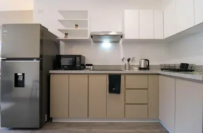 a kitchen with white cabinets and a stainless steel refrigerator at Qoyllur by Wynwood House in Cusco