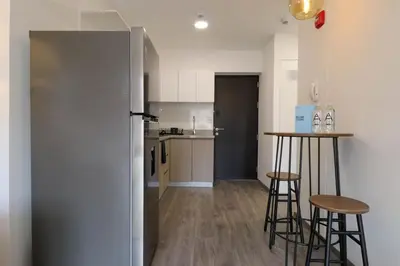 a kitchen with a refrigerator and two bar stools at Qoyllur by Wynwood House in Cusco
