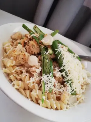 a white bowl of pasta with vegetables and cheese at Hotel Villa Capricce in Puente Piedra