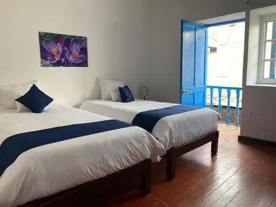 two beds in a room with a door to a balcony at Runa House in Cusco