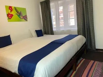 a bedroom with a large bed with blue and white sheets at Runa House in Cusco