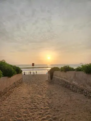 a sunset on a sandy beach with people on the beach at 