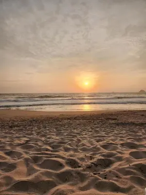 a sunset on a beach with footprints in the sand at 