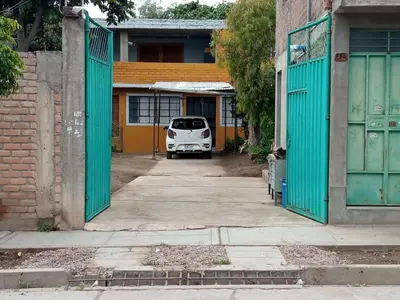 a white car parked in a parking lot between two buildings at Casa Hospedaje in Ayacucho