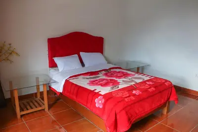 a bed with a red blanket and a glass table at Yanachaga Hotel - Oxapampa in Oxapampa