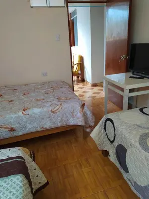 a room with two beds and a table and a mirror at Casa de Campo y Hospedaje Irma in Lunahuaná