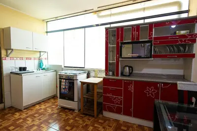 a kitchen with red cabinets and a stove top oven at Depawanka 3 Departamento amoblado y equipada in Huancayo