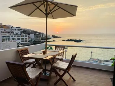 a wooden table with chairs and an umbrella on a balcony at Departamento COCO - San Bartolo in San Bartolo