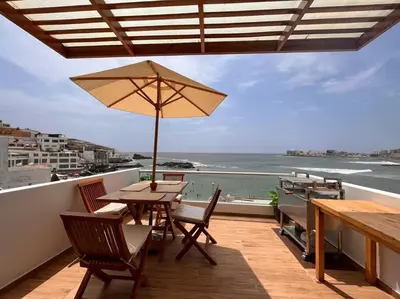 a table and chairs with an umbrella on a balcony at Departamento COCO - San Bartolo in San Bartolo