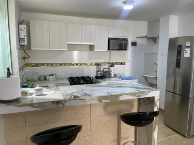 a kitchen with marble counter tops and a refrigerator at Acogedor departamento en Los Olivos 3 dormitorios in Lima