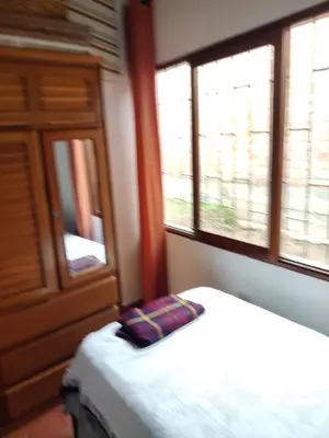 a bedroom with a bed and a cabinet and two windows at bungalows in Santa Rosa