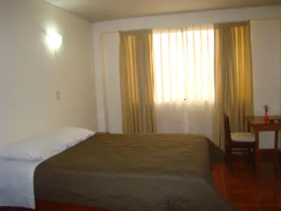 a bedroom with a bed and a desk and a window at Kibo Hotel in Ayacucho