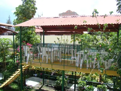 a deck with tables and chairs in a garden at Kibo Hotel in Ayacucho