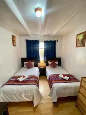 two beds in a room with blue curtains at Amira's House Cusco in Cusco