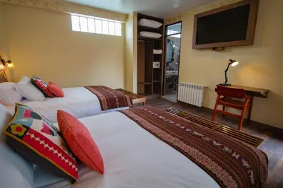 a hotel room with two beds and a television at Valle Del Sol in Urubamba