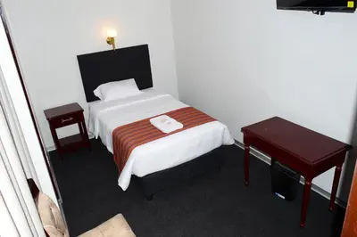 a small bedroom with a bed and a table at Hotel Santa Felicita - Centro Histórico in Huancayo