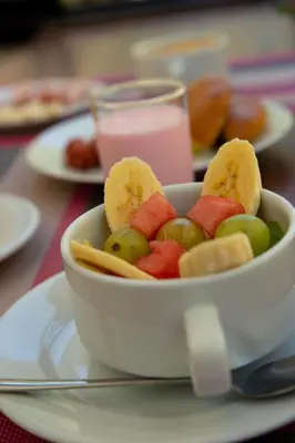 a bowl of fruit on a plate with a glass of milk at Susanna Inn MachuPicchu Hotel in Machu Picchu