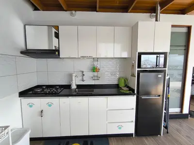 a kitchen with white cabinets and a stainless steel refrigerator at Lindo chalet en PUCUSANA in Pucusana