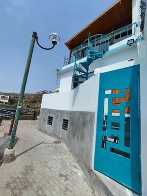 a blue door on a white building with a street light at Lindo chalet en PUCUSANA in Pucusana