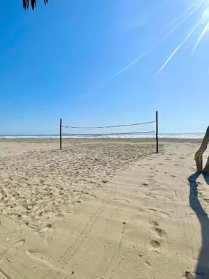 a person standing on a beach with a volleyball net at Bungalows frente al mar en playa Wakama in San Vicente de Cañete