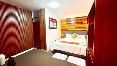 a bedroom with a bed with a wooden headboard at Hotel SumacPlaza in Ayacucho