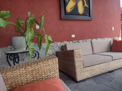 a living room with a couch and wicker chairs at Casa Cusco in Cieneguilla