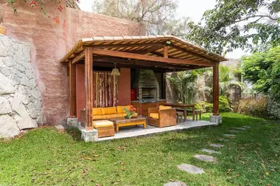a wooden pavilion with chairs and a table at Casa Cusco in Cieneguilla