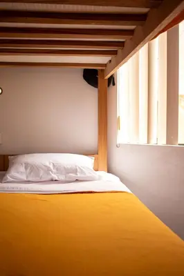 a bed with a yellow blanket and a window at Temazcal Hostel in Lima