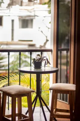 a table and two chairs on a balcony with a window at Temazcal Hostel in Lima