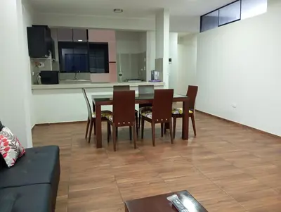 a dining room with a table and chairs and a kitchen at La campiña in Lima