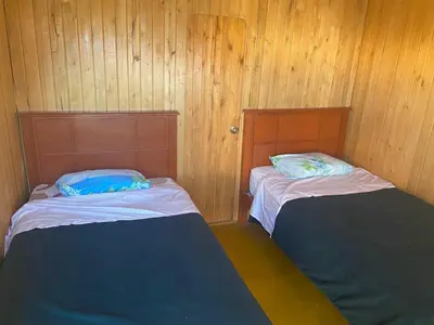 two beds in a room with wood paneled walls at Coco y Ainhoa Lodge in Paracas
