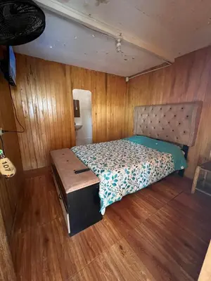 a bed in a room with wooden walls and wood floors at Coco y Ainhoa Lodge in Paracas