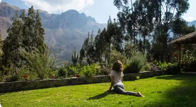 a woman sitting on the grass looking at the mountains at SAMAY WASI Rest house in Ollantaytambo