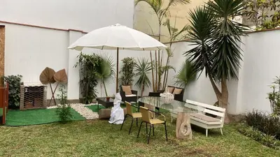 a patio with a glass table with chairs and an umbrella at 102 habitacion con baño y cocina e ingreso independiente in Lima