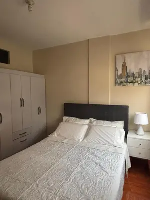 a bedroom with a large bed with white sheets and a cabinet at Light department in Lima